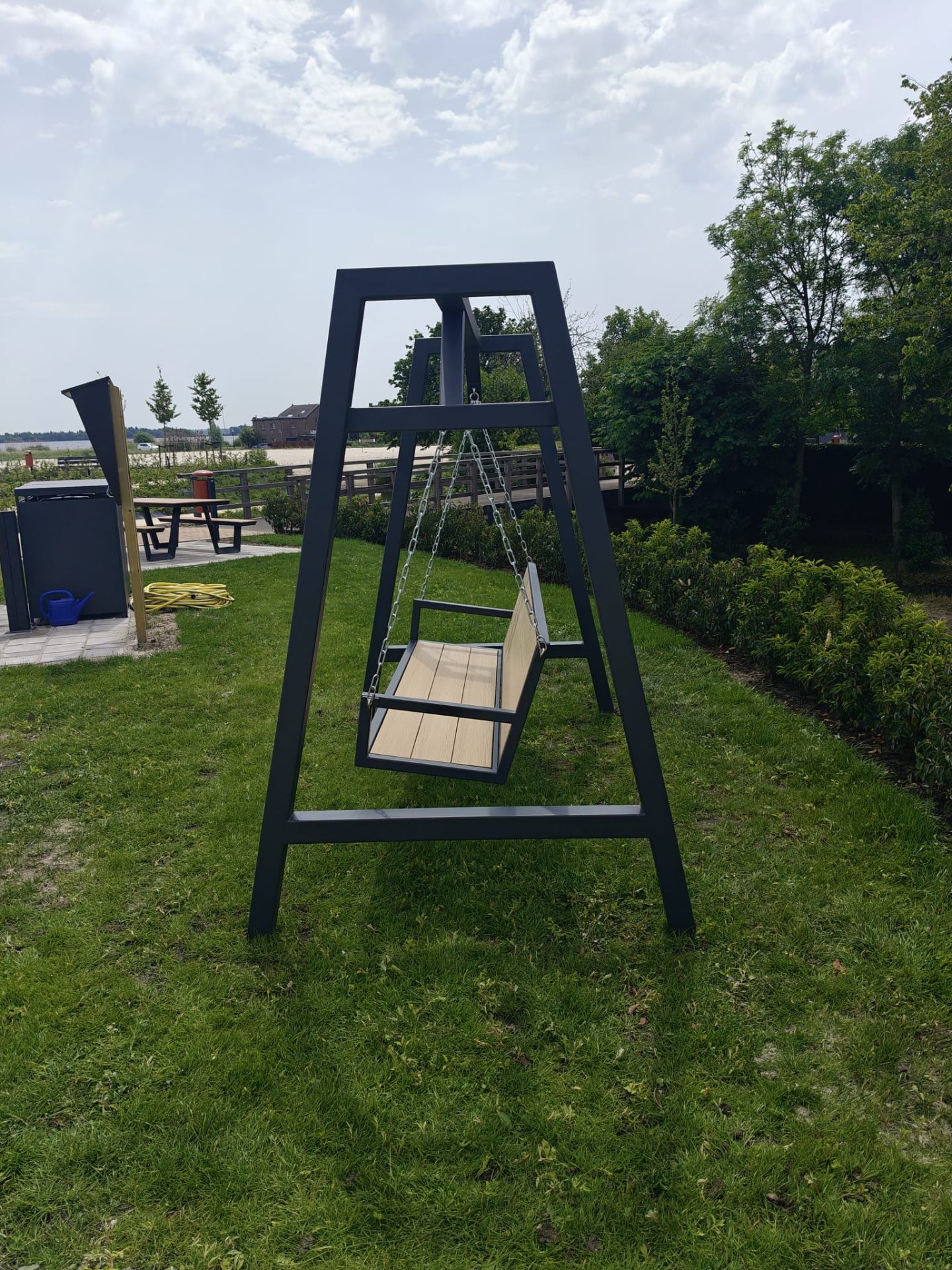 Schommelbank — Antraciet — tuinmodel · Buitenleven · A-frame schommelbank in stalen profiel met composiet planken en geïntegreerde zijtafels. Verkrijgbaar in meerdere kleuren en uitvoeringen.